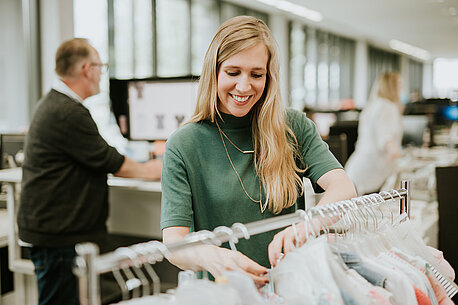 Vera steht vor einer Kleiderstange mit Ernsting's family-Mode.