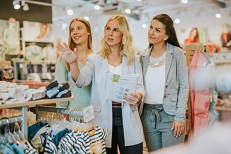 Drei Frauen tauschen sich in einer Ernsting's family-Filialen über die Präsentation der Ware aus.